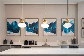 Three blue and white paintings hang on a wall above a kitchen counter in the clubhouse at harbor pointe apartments, bayonne